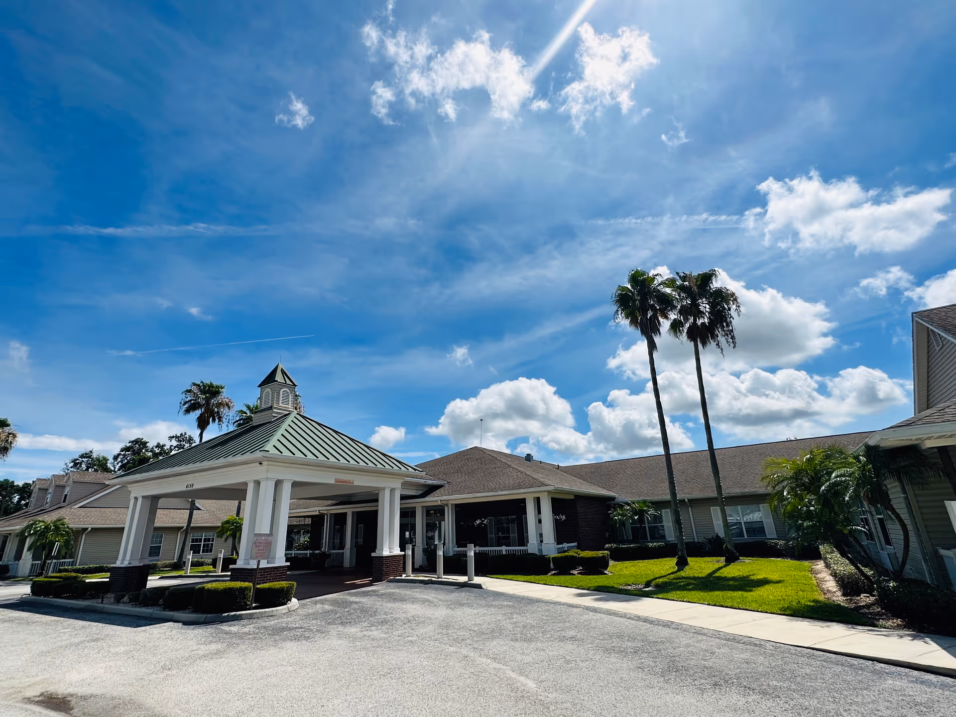 Front view of Hawthorne Inn of Lakeland with porte-cochère and palm trees under blue sky