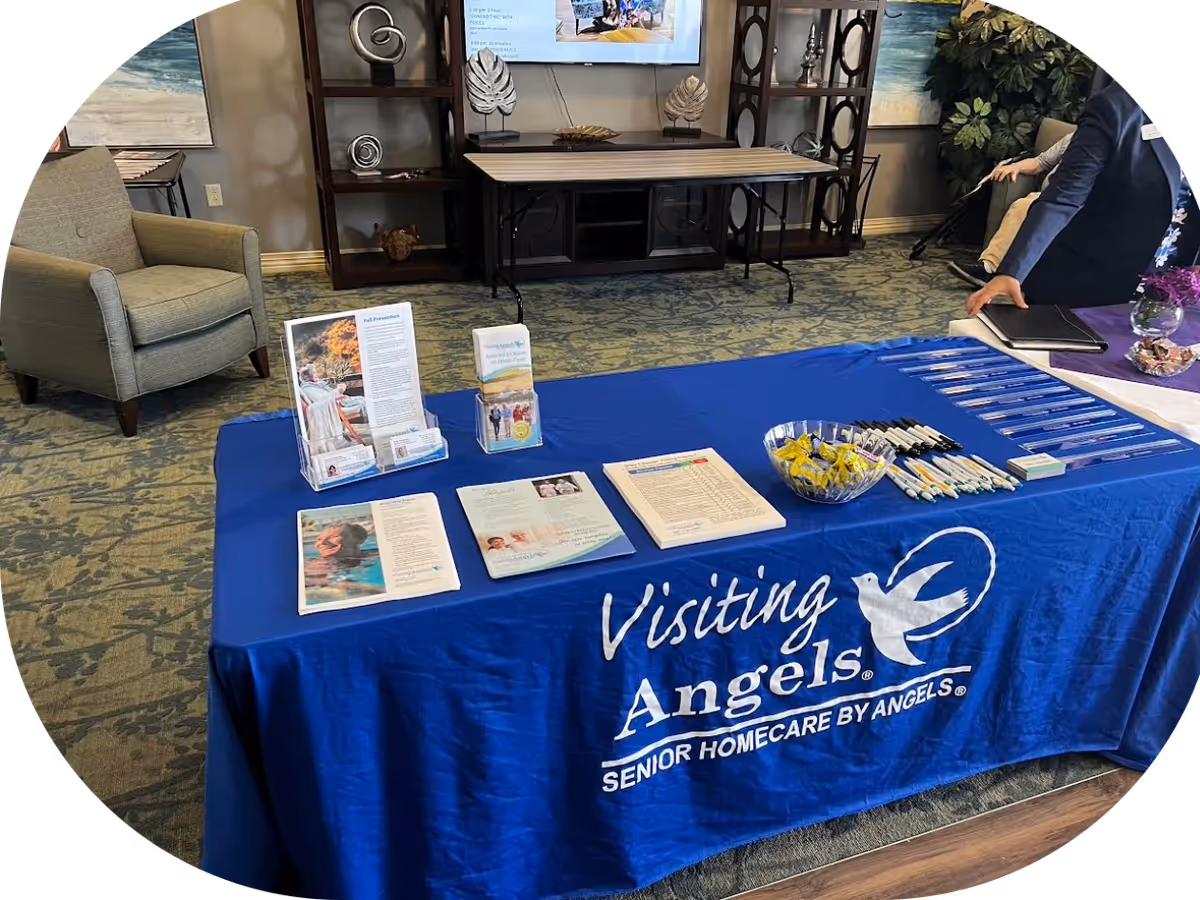 Lobby scene with a blue Visiting Angels table and printed marketing materials.