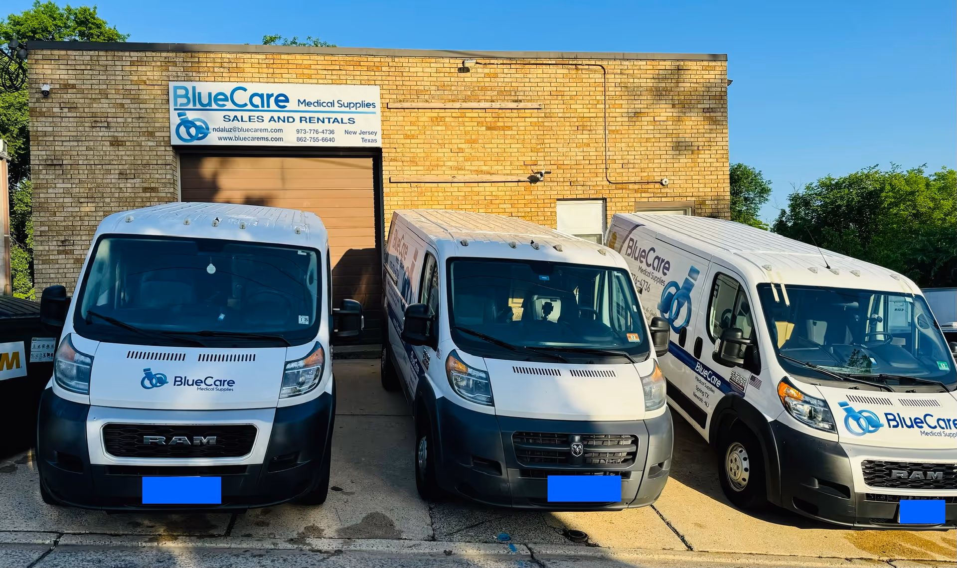 Three BlueCare Medical Supplies delivery vans parked in front of a brick building.