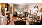 Bright living room in a senior facility with sofa, chairs, lamps, and built-in cabinets.
