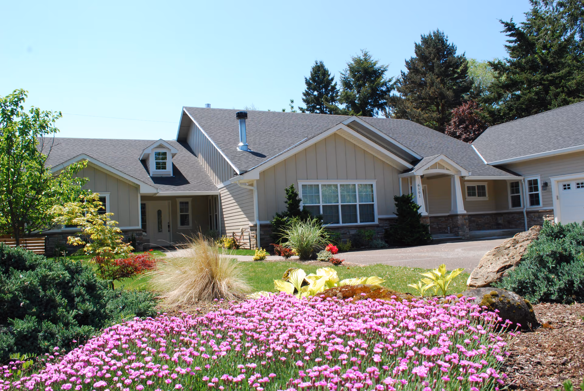 Front exterior view of a beige senior living facility with landscaped garden.