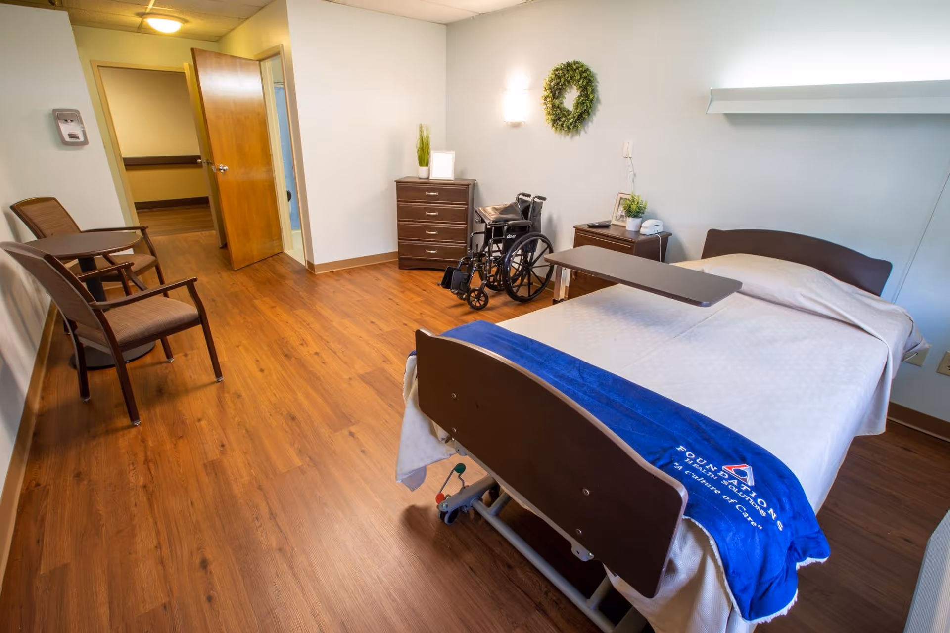 Bedroom in Timberland Ridge Skilled Nursing and Rehabilitation with hospital bed, wheelchair, dresser, and seating.