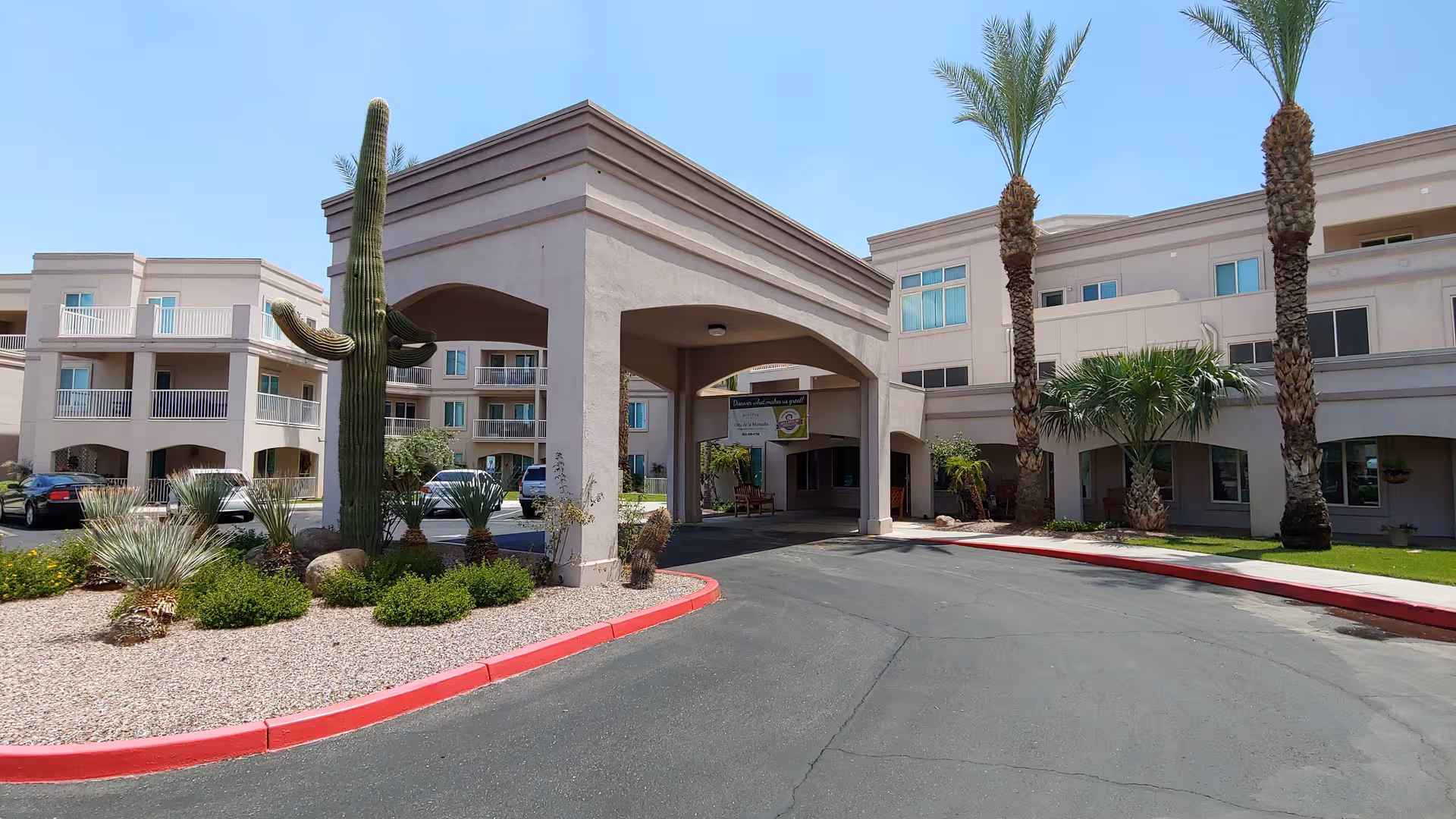 Front exterior of Holiday Vista de la Montana with palm trees, archway entry, and curved driveway.