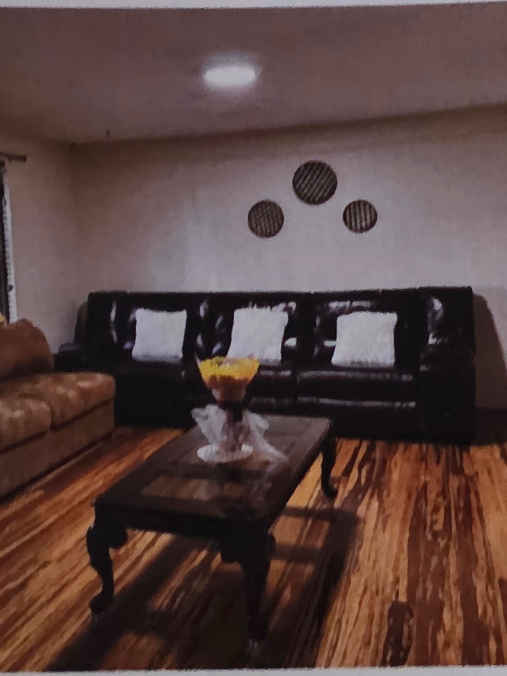 Cozy living room with black leather sofas, a wooden coffee table, and circular wall decor.