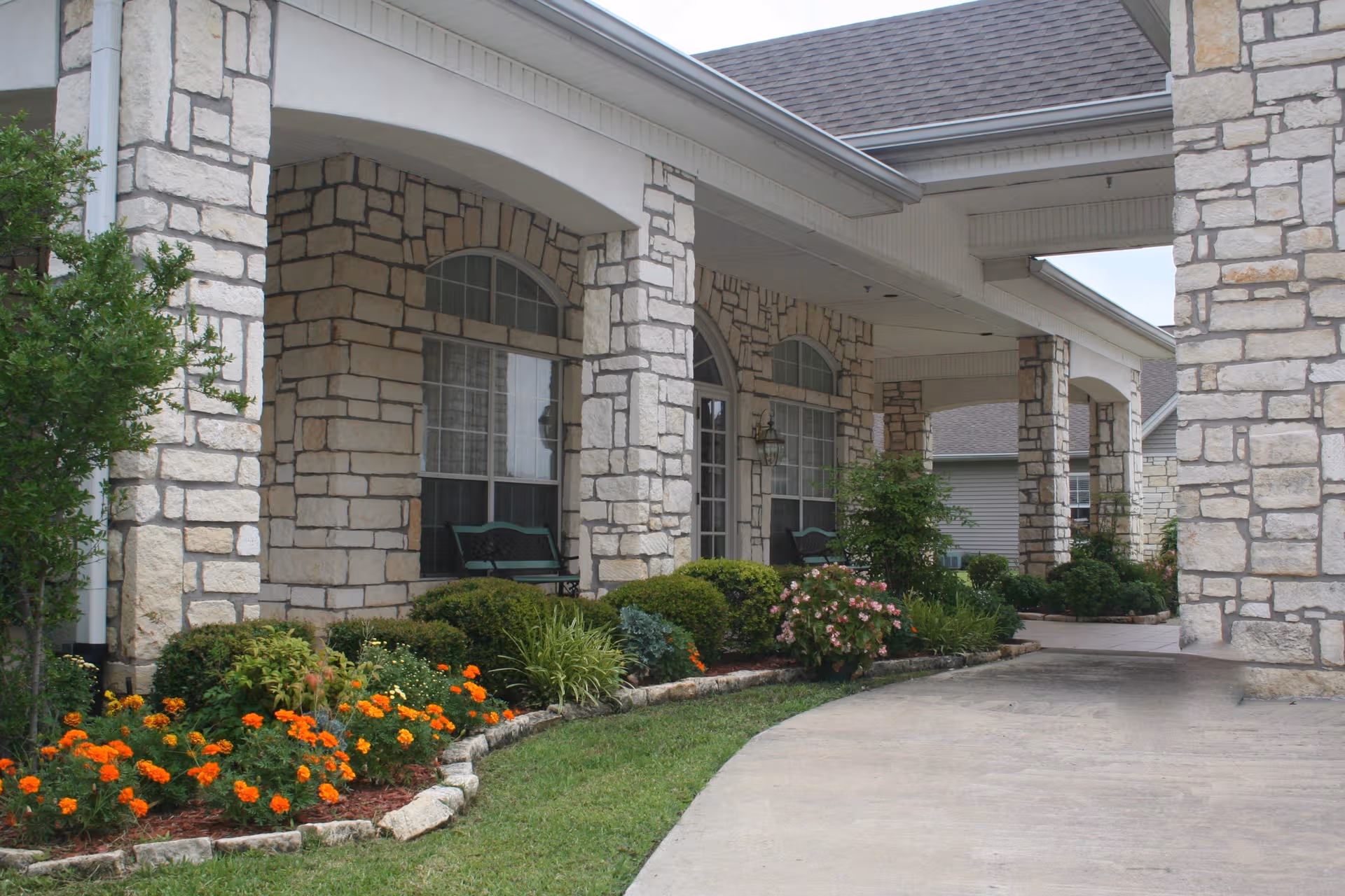 Stone Brook exterior with stone facade, arched windows, and landscaped walkway.