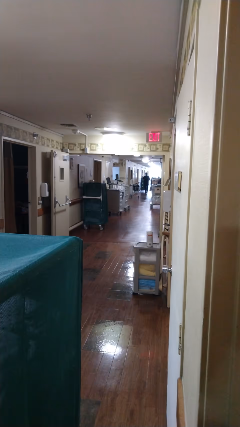 Long hallway in a senior living facility with carts and closed doors.