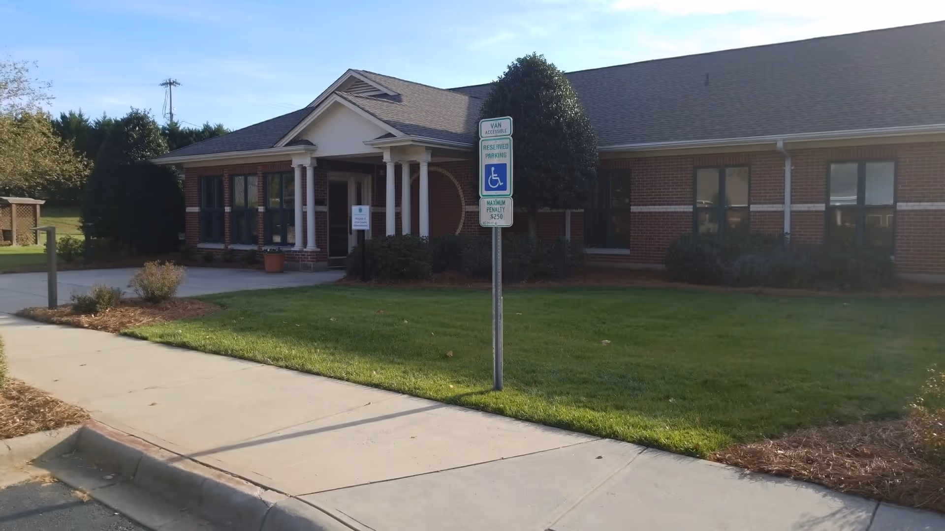 Brick senior care facility exterior with a covered entrance and manicured lawn.