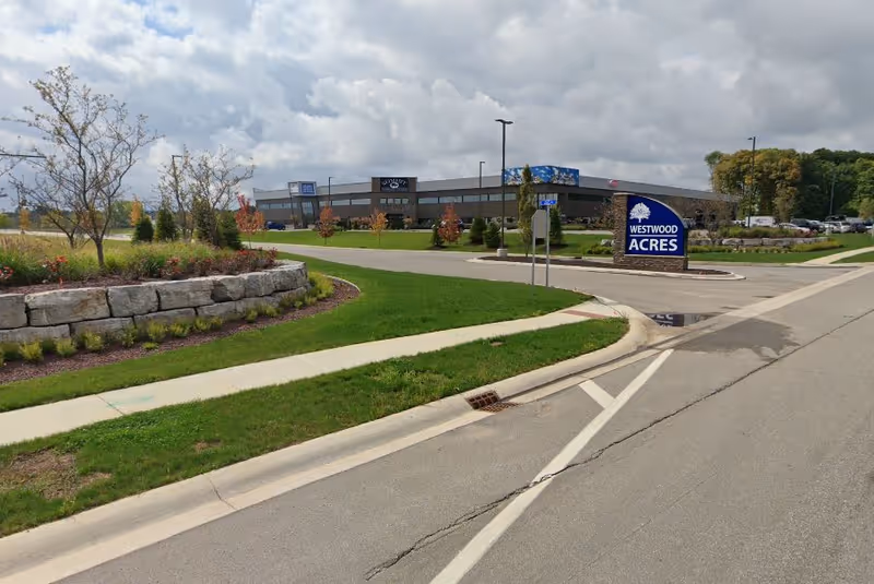 Exterior view of a senior living facility with landscaping and a front sign.