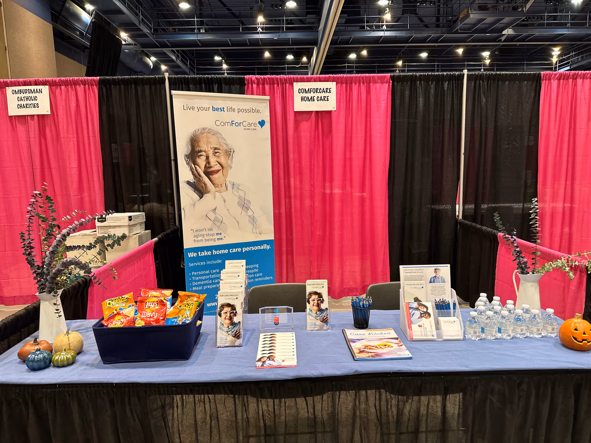 Exhibit booth for ComForCare Home Care Modesto with pink curtains and brochures.
