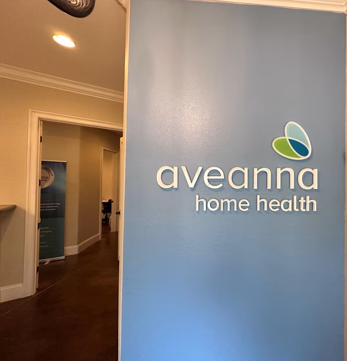 Interior hallway featuring a blue wall with the Aveanna Home Health logo.