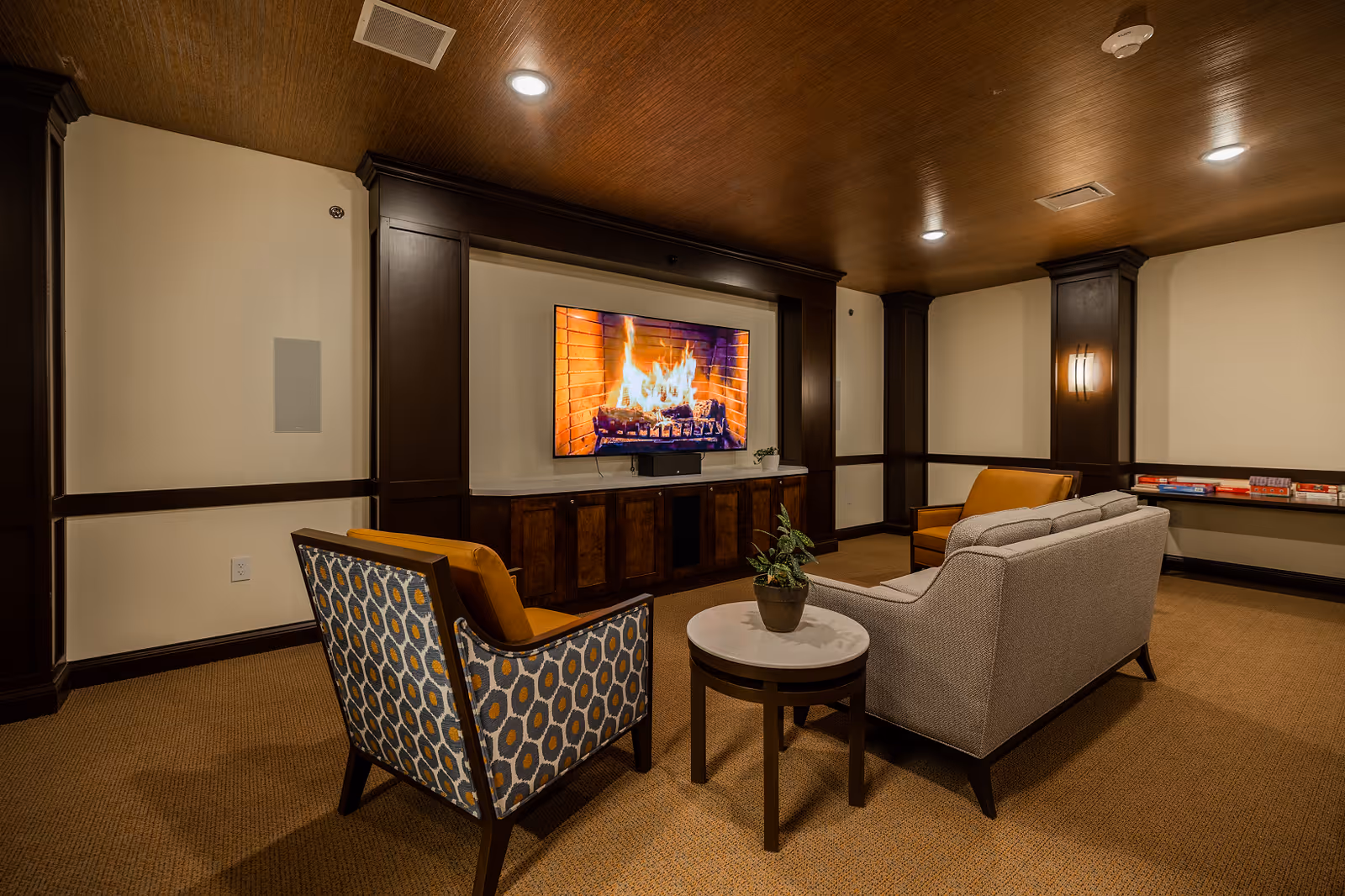 Cozy lounge area with fireplace, TV, and seating in a wood-accented living room.