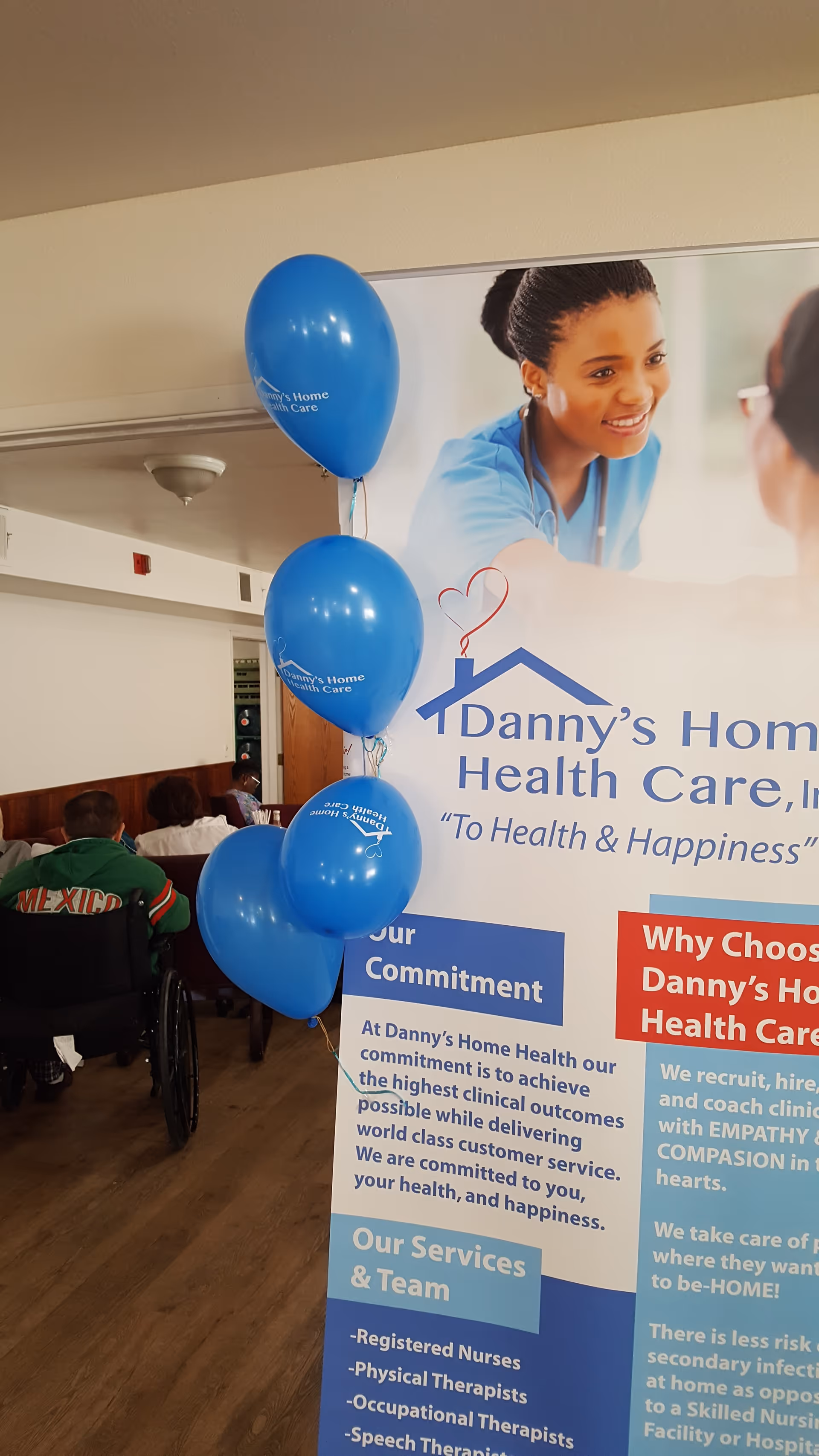 Indoor promotional banner for Danny's Home Health Care in a lobby with blue balloons.