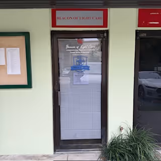 Entrance door framed by pale green wall; Beacon of Light Care sign above.