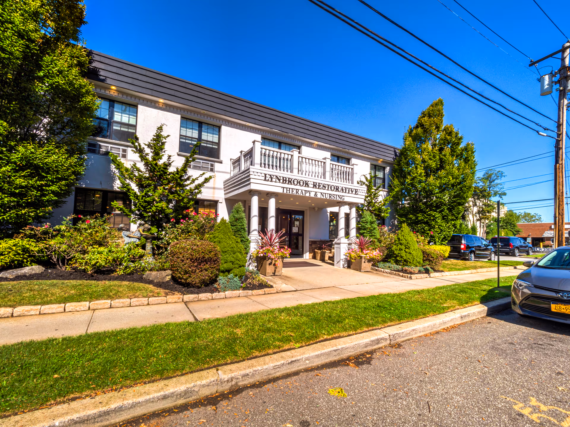 Exterior view of Lynbrook Restorative Therapy and Nursing building with landscaping and entrance.