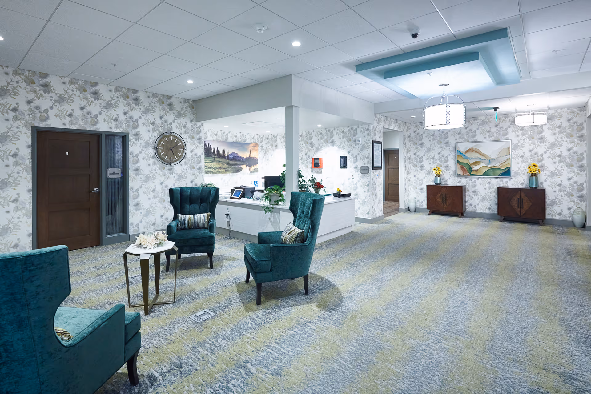 Rockwood Retirement at Whitworth lobby: teal chairs, floral wallpaper, reception desk, and artwork.