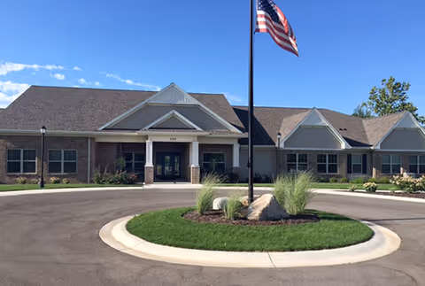 Front view of Green Acres of Wayland II facility with circular driveway and flagpole.