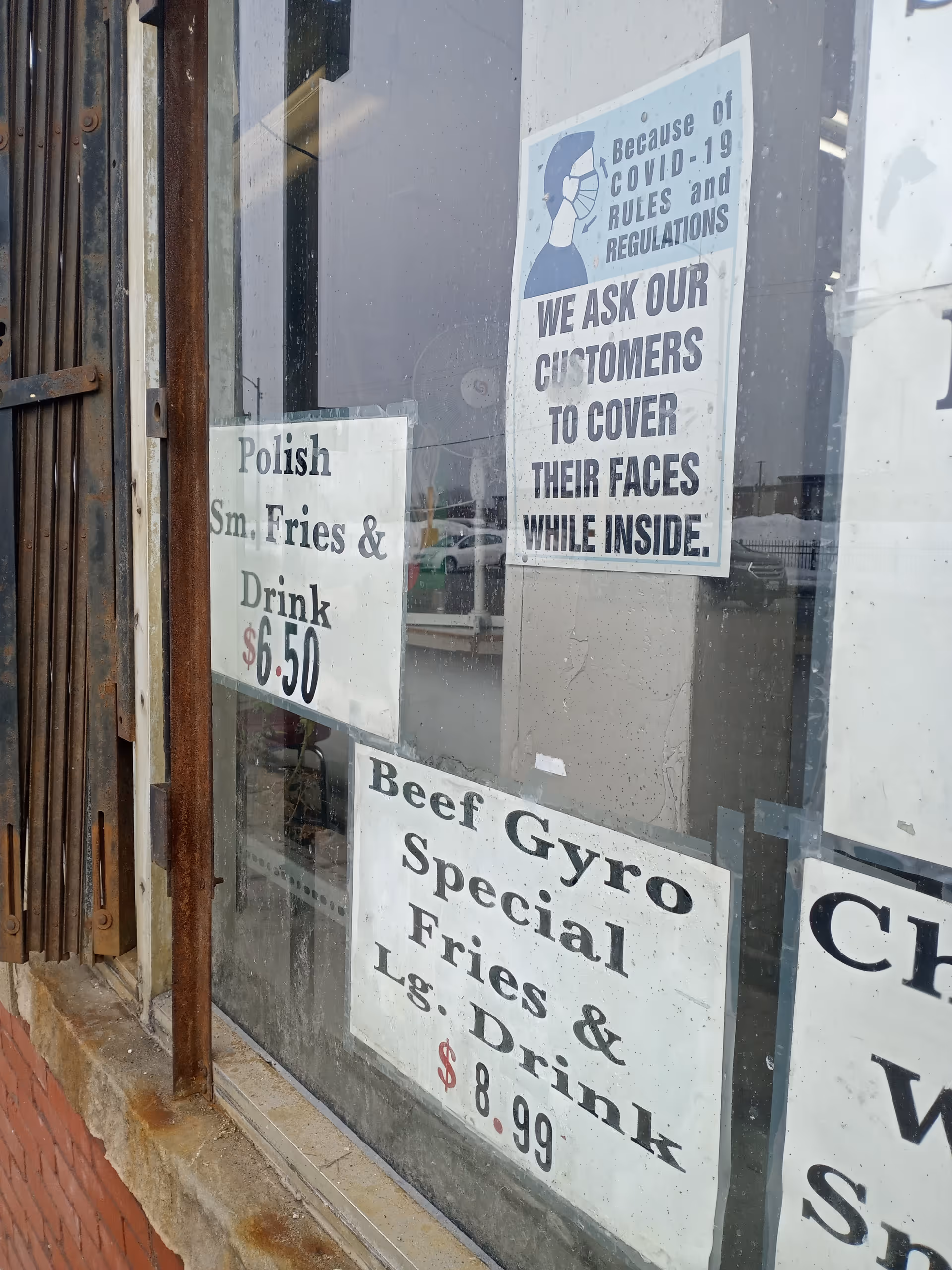 Rusty storefront window with signs advertising fries and drinks