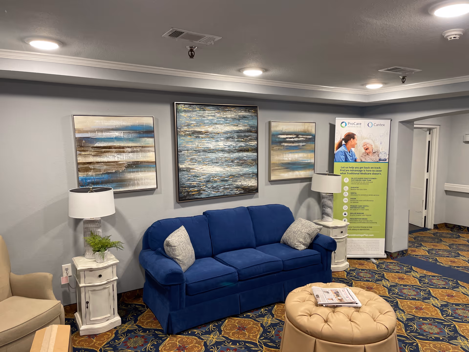 A blue sofa and beige chairs sit in a cozy living room with wall art.