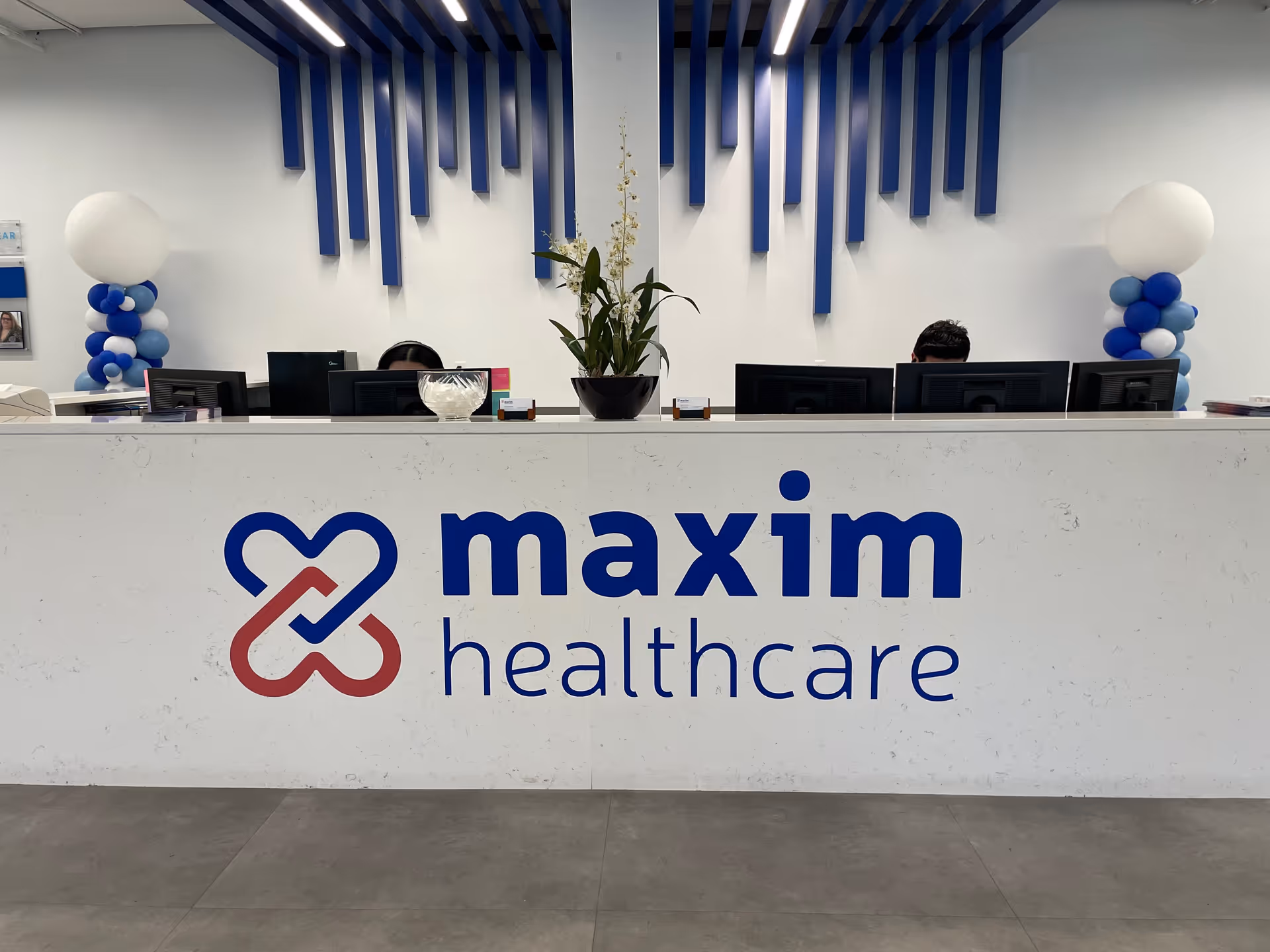 Reception desk inside Maxim Healthcare Columbia headquarters featuring blue accents and logo.