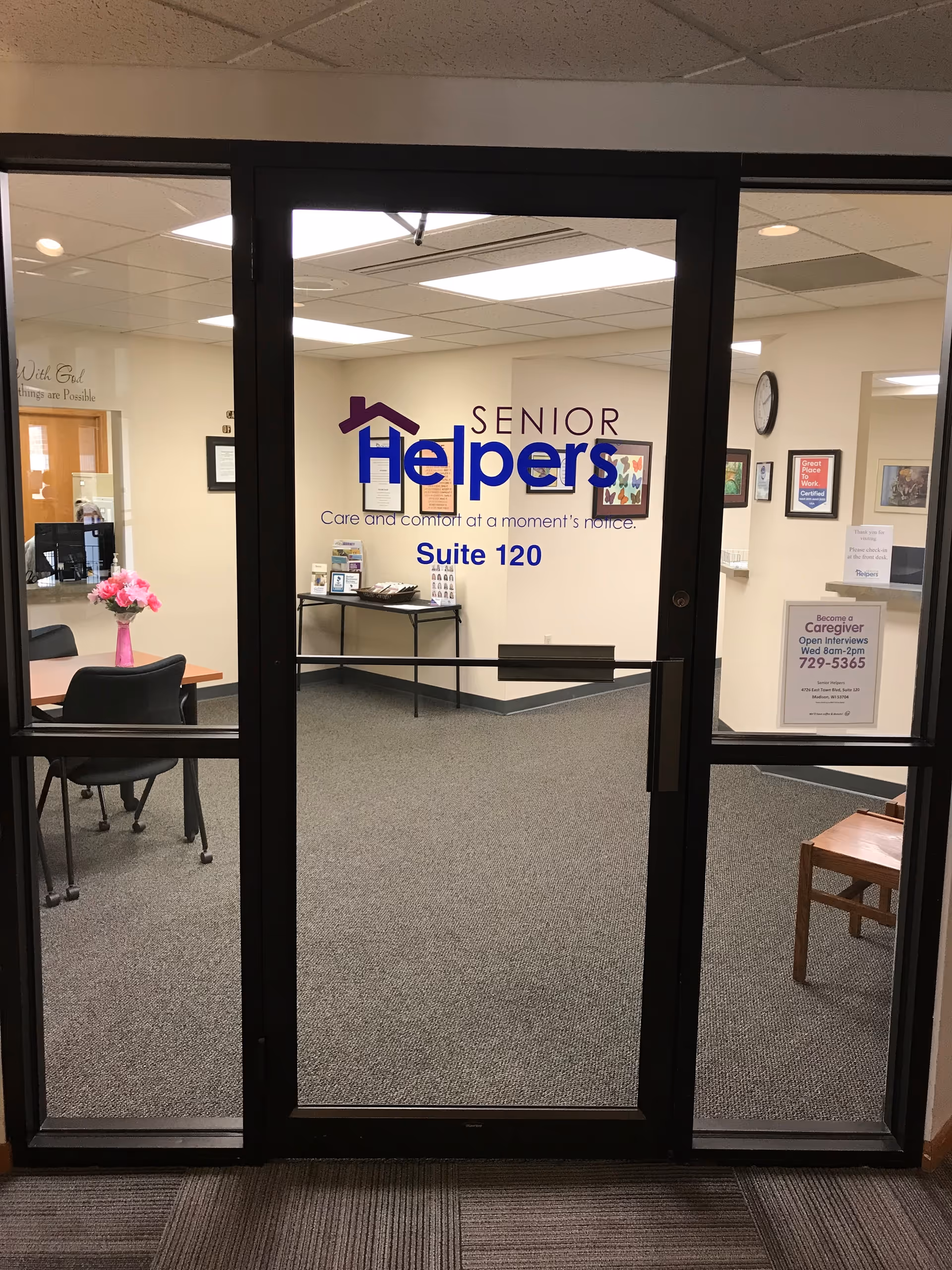 Glass doors open to a Senior Helpers lobby with chairs, a table, and framed artwork.