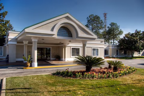 Front exterior of Grand Boulevard Health and Rehabilitation Center with arches, columns, and landscaping.