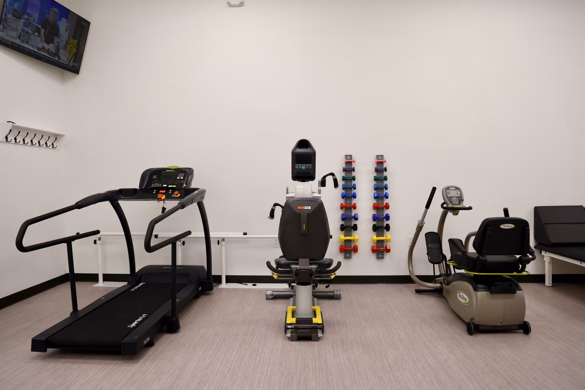 Fitness room with treadmills, a cycling machine, and weights in a clean facility.