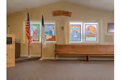 A waiting area inside Valley Manor Care Center with a flag and wooden benches.