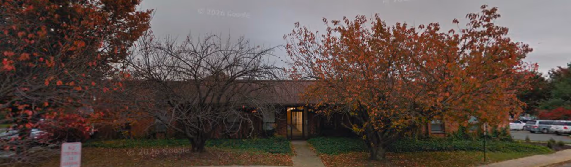 Spero Hospice facility entrance framed by autumn trees and a parking lot.