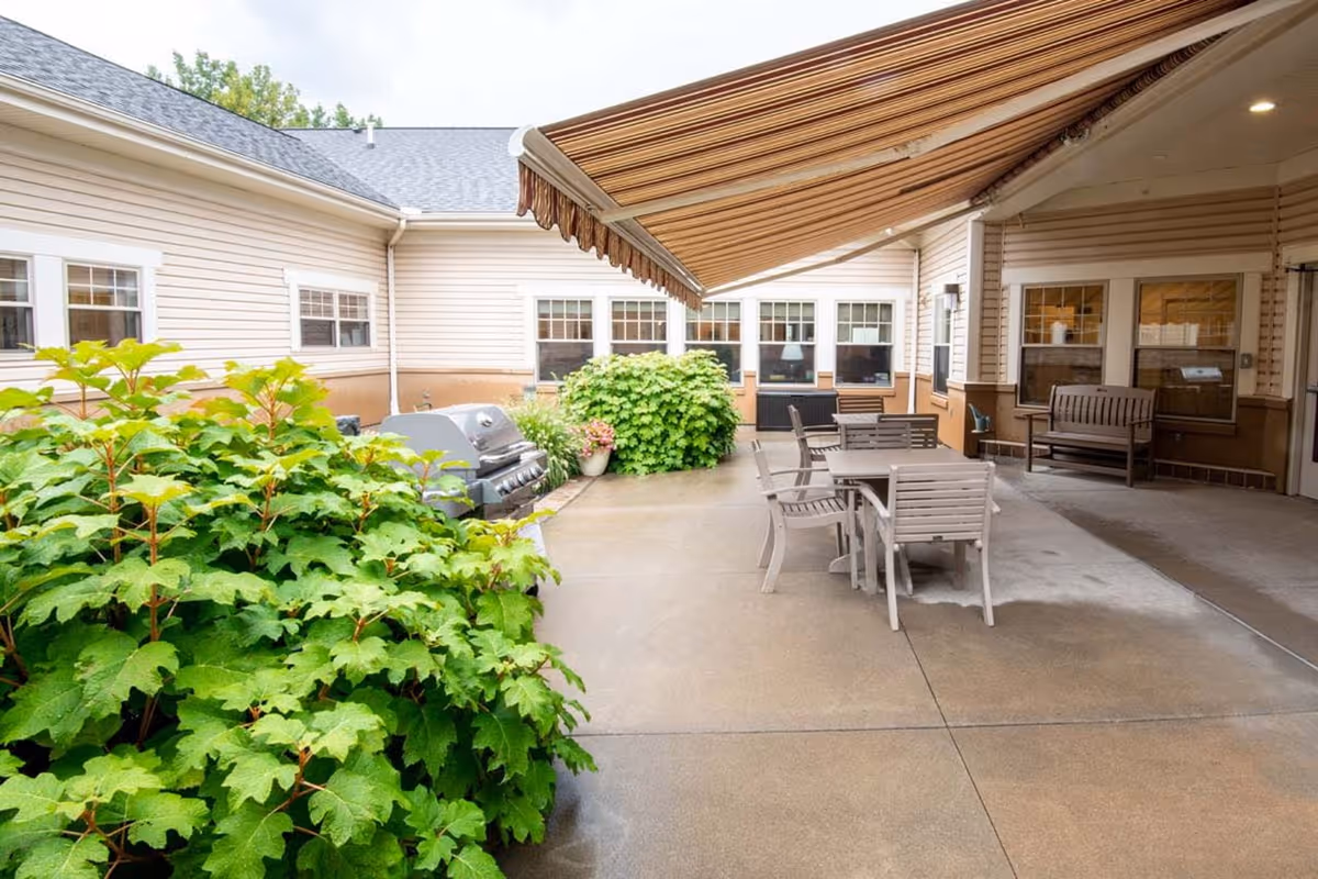 Outdoor courtyard with table, chairs, and awning beside a beige building.