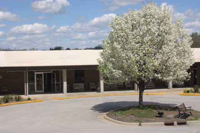 Exterior view of Beth Haven Nursing Home with a blooming tree by the entrance.