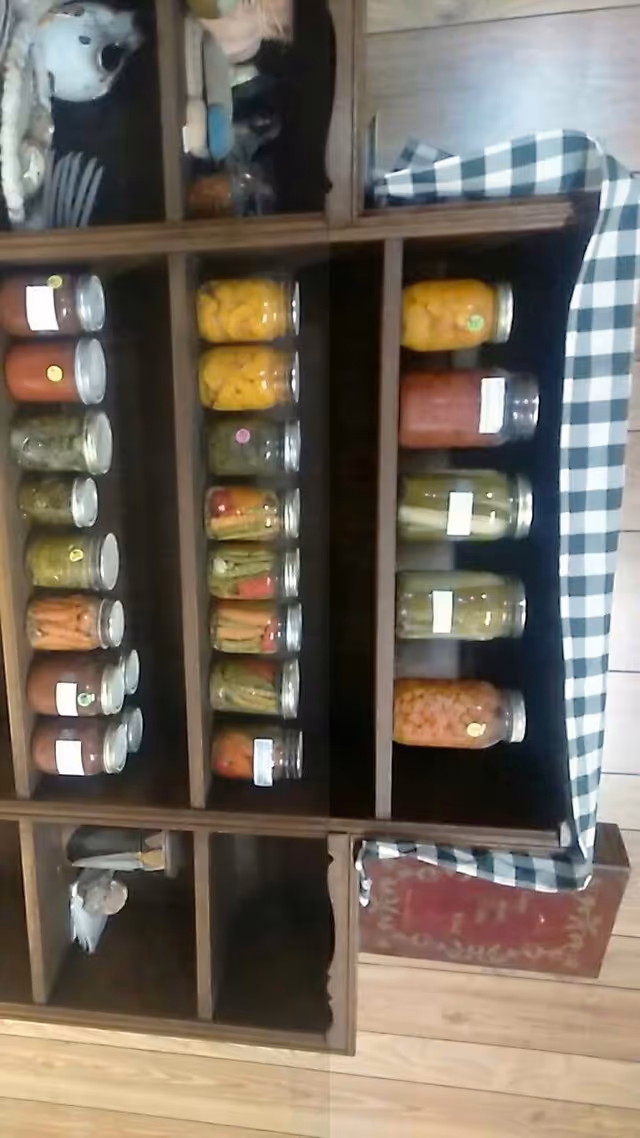 Wooden cabinet with glass jars of colorful preserved vegetables.