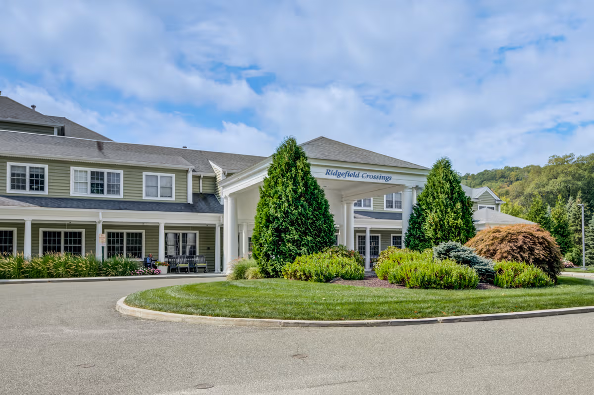 Exterior view of Ridgefield Crossings senior living facility with landscaped entrance and circular driveway.