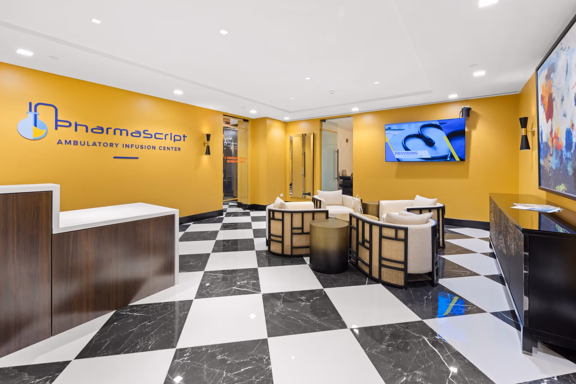 Bright yellow lobby with reception desk, seating cluster, and a checkered black-and-white tile floor.