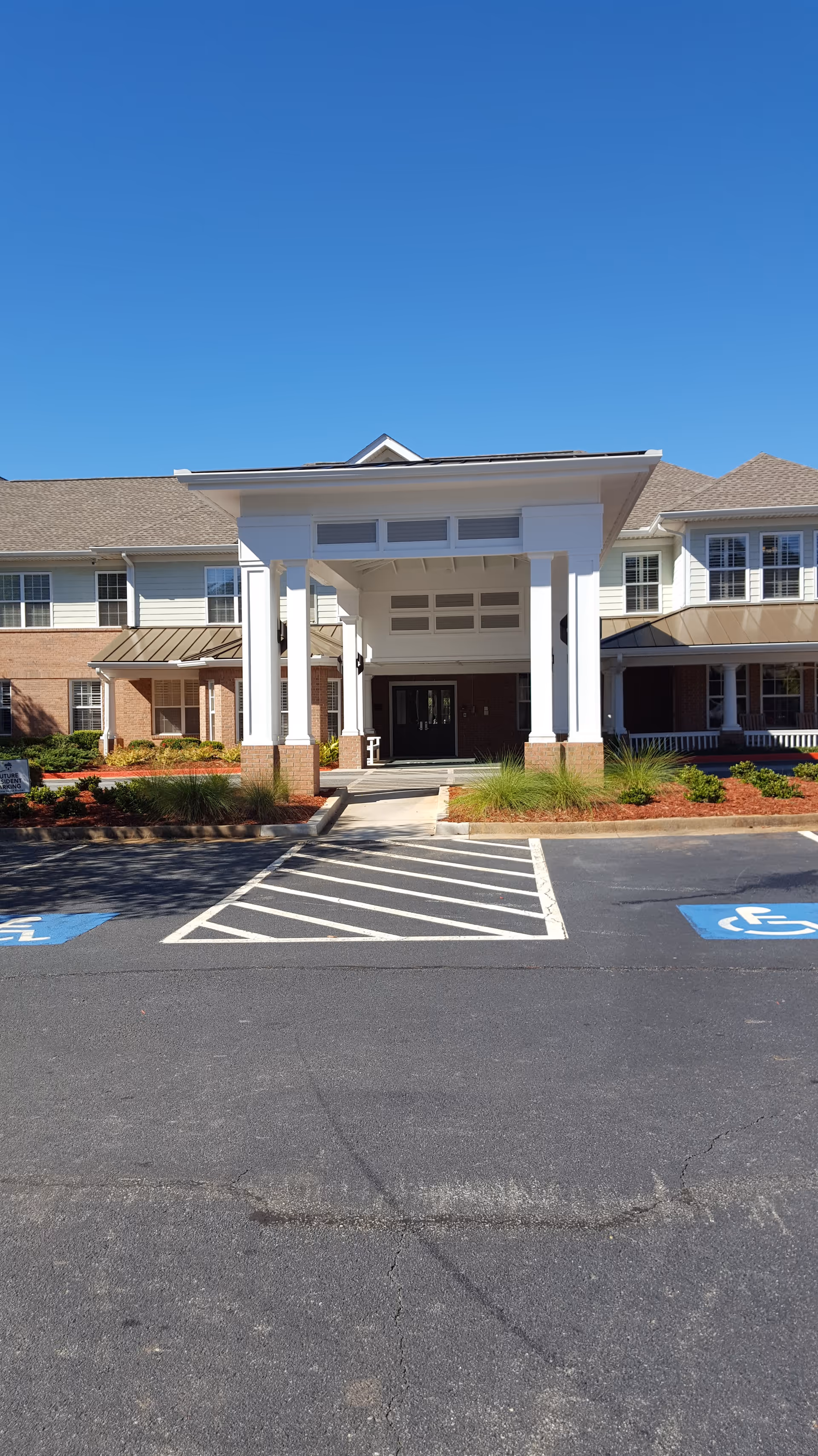 Front exterior of The Cohen Home senior living facility with a covered entrance and handicap spots.