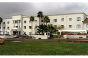 Exterior view of Christian Care Manor IV, a cream-colored senior living facility with palm trees.