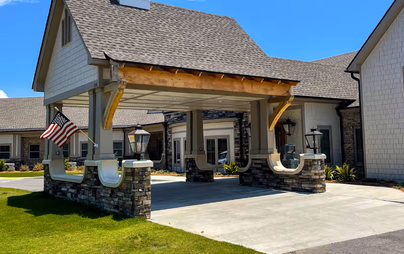 Front exterior view of Westminster Memory Care with porte-cochère and American flag.