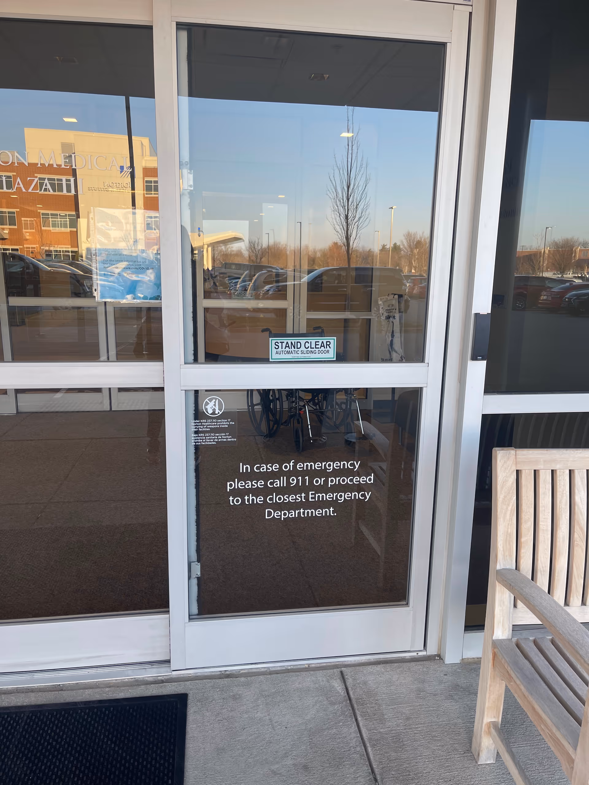 Glass entrance doors of Norton Healthcare Medical Plaza III Brownsboro with a bench outside.