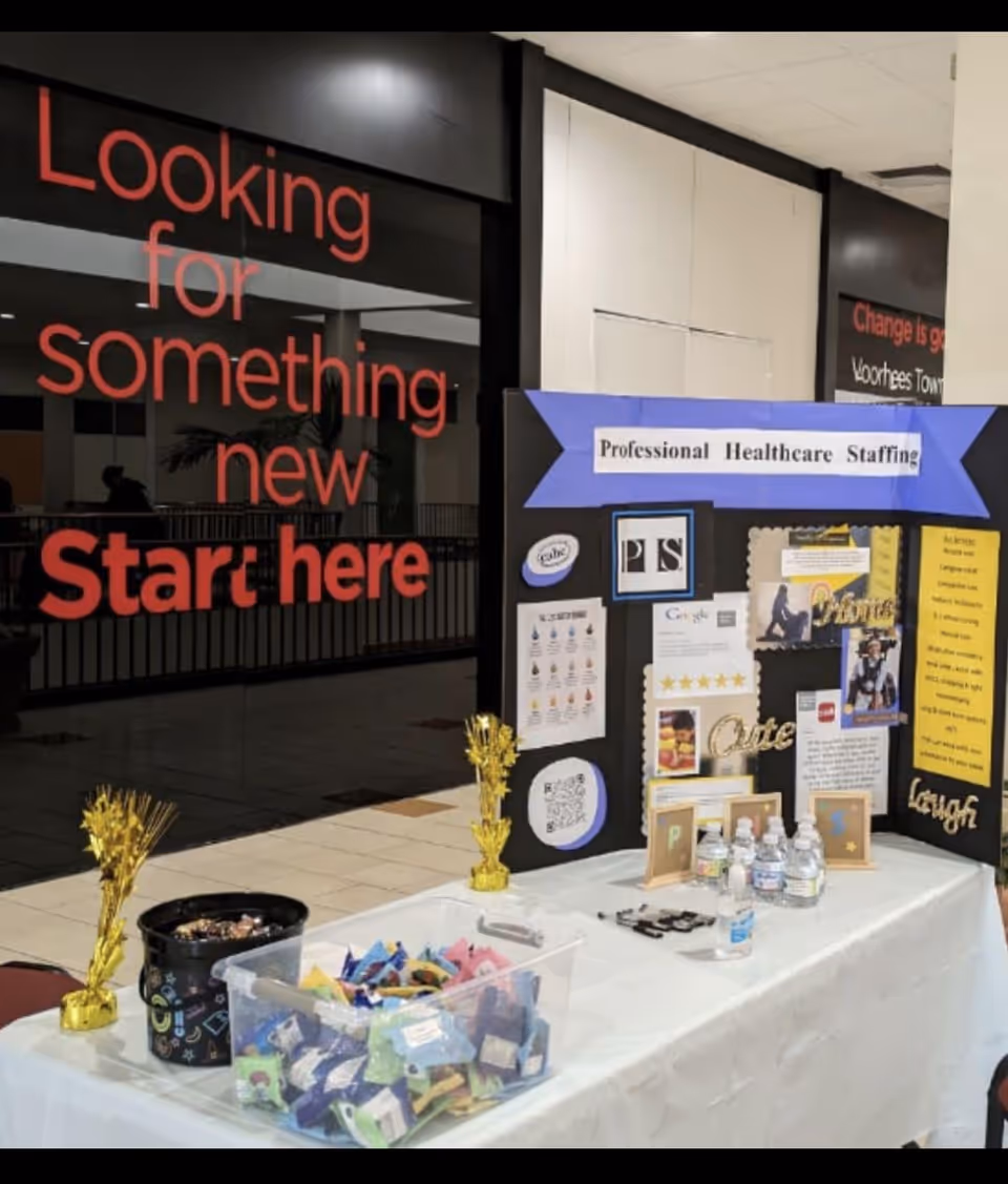 Indoor display booth for Professional Healthcare Staffing with tables, posters, and candy.