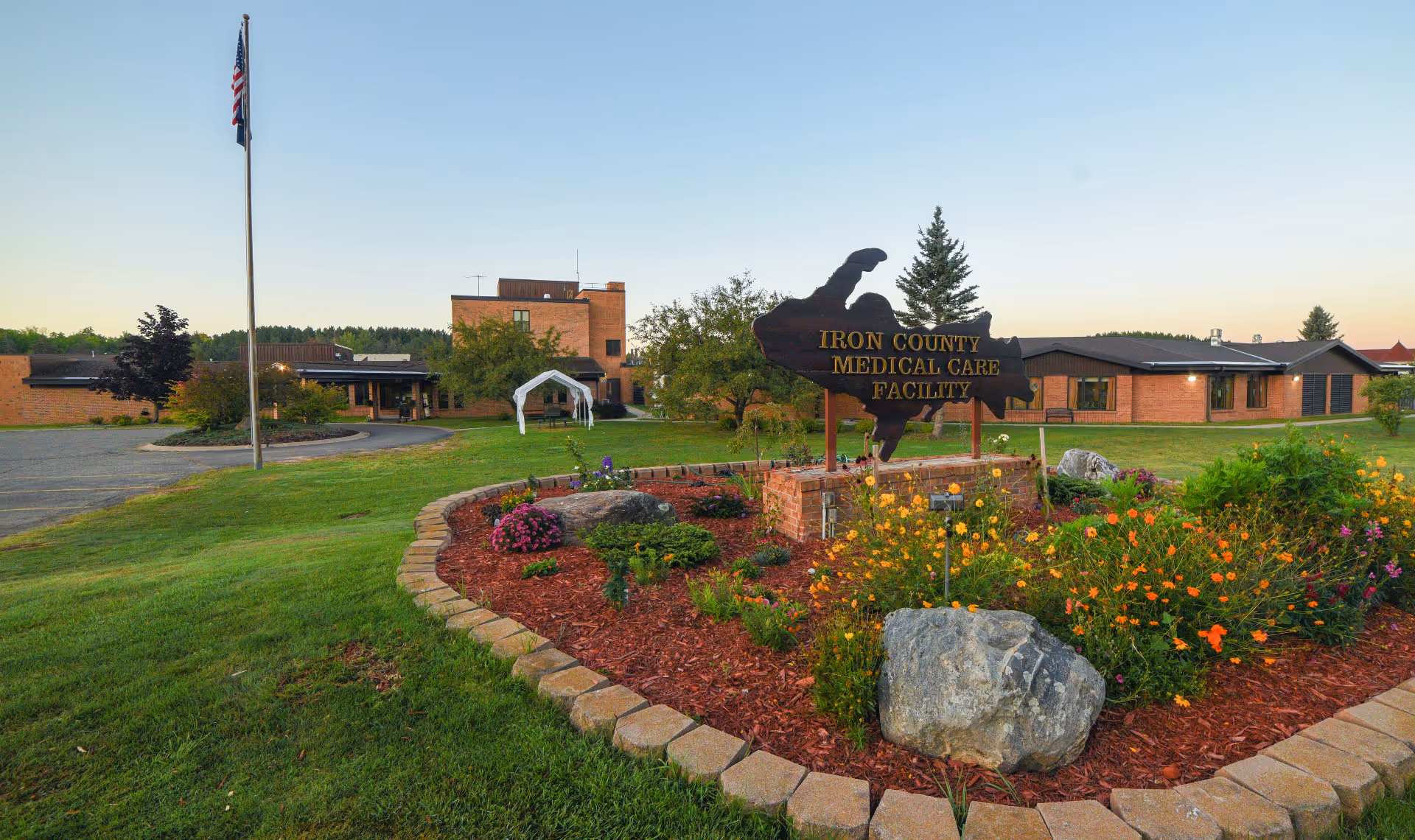 Exterior view of Iron County Medical Care Facility with landscaping, flag, and sign.