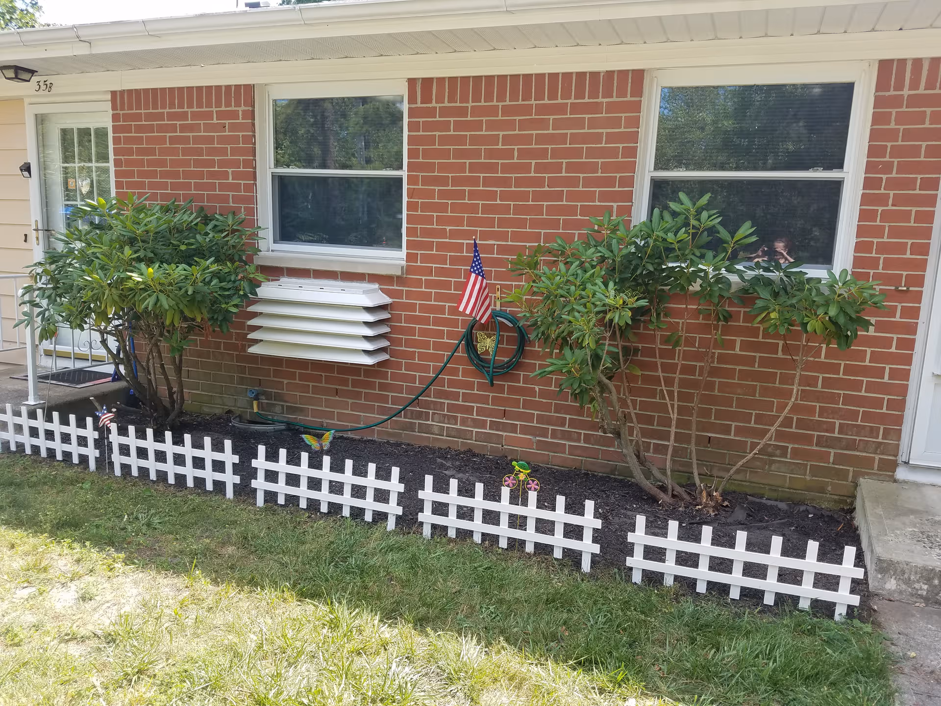 Brick exterior of Crestwood Village Co-Op IV with small garden and white picket fence.