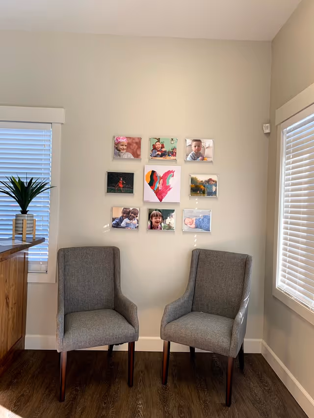 Two gray chairs surround a wall with a colorful photo collage.
