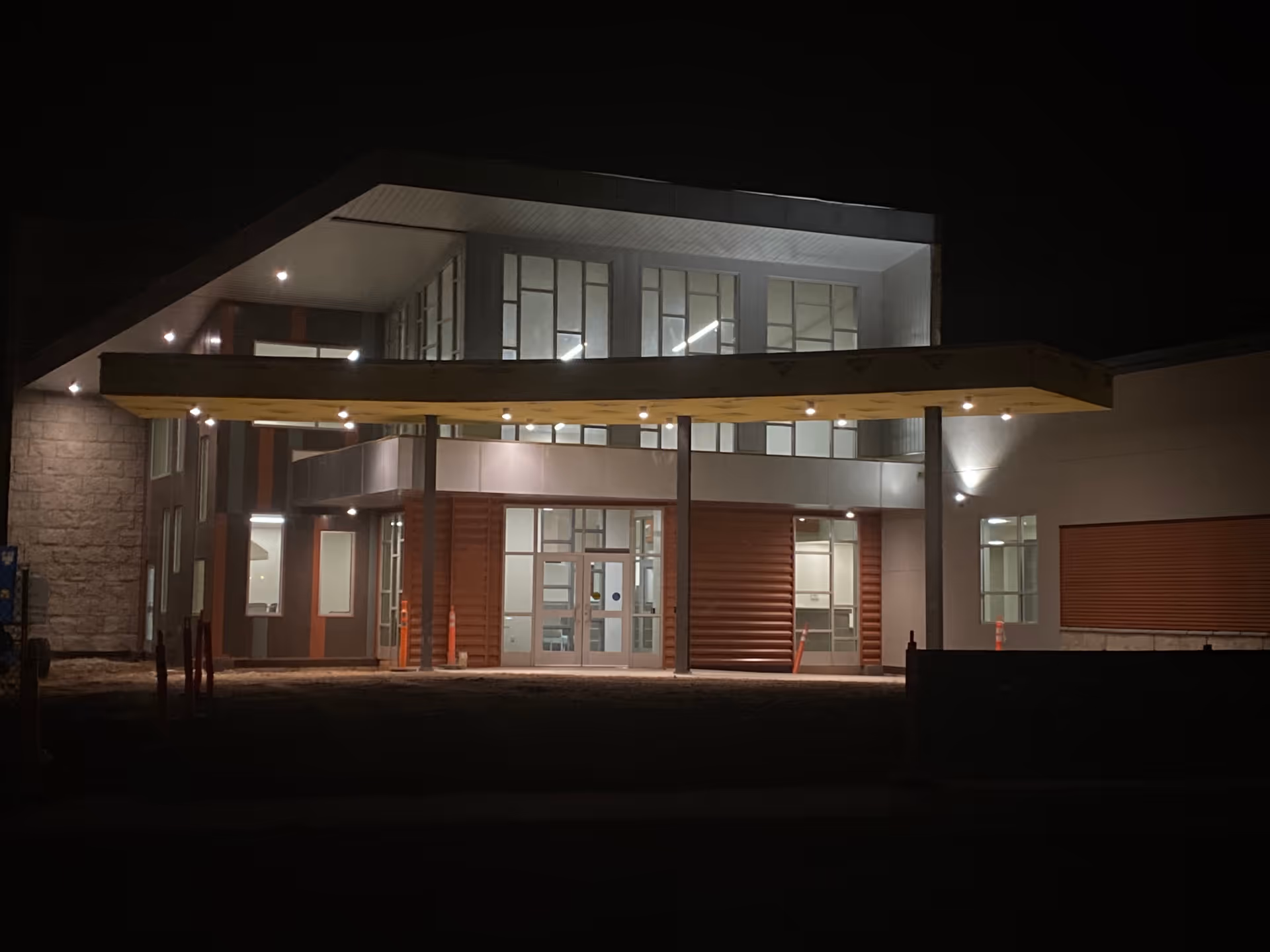 Nighttime exterior of a modern senior living facility with illuminated glass entrance under a canopy