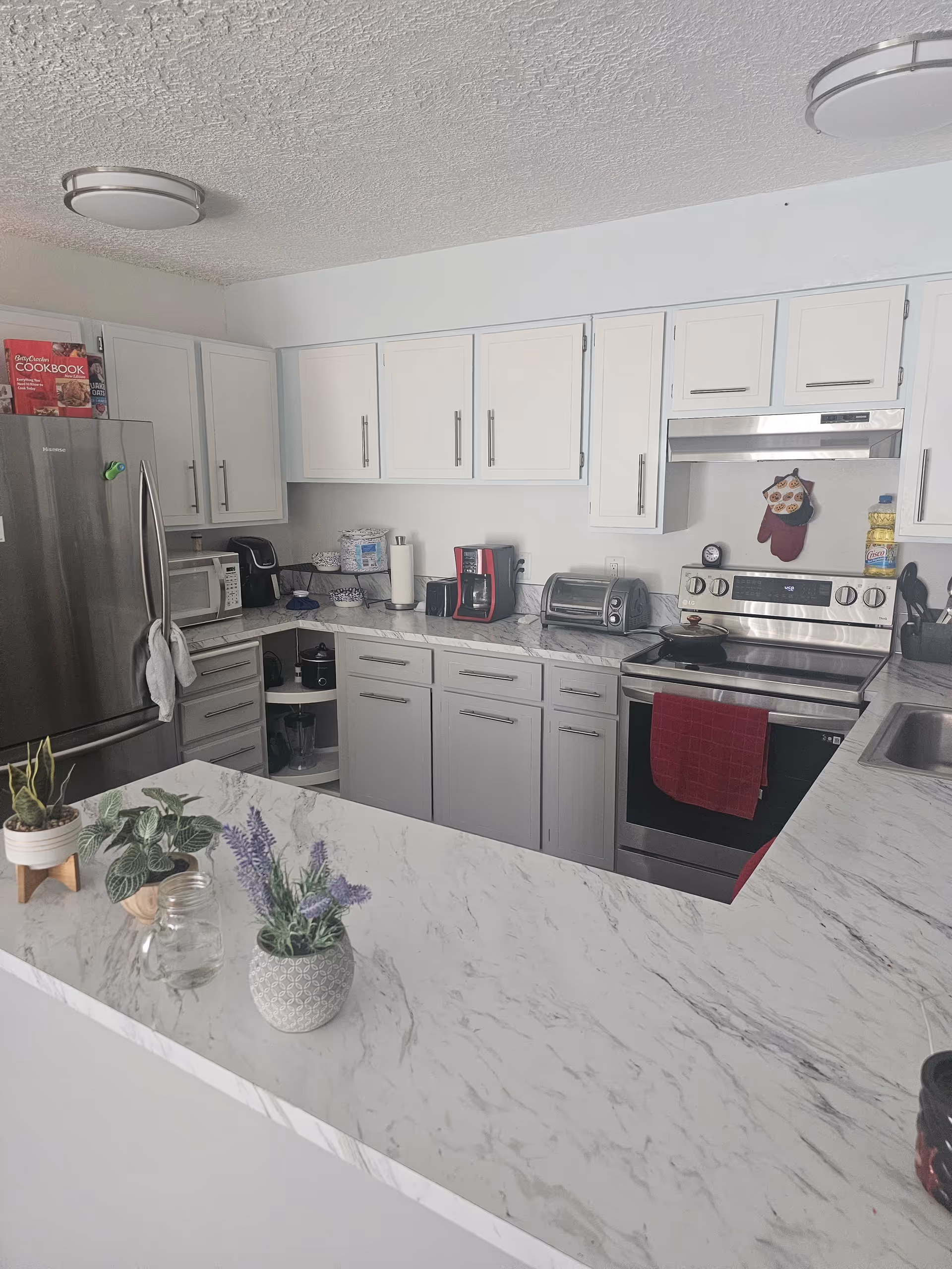 Bright kitchen with white cabinets, marble countertops, and stainless steel appliances in a senior facility.