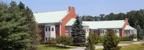 Exterior view of Bedford Hills Center building with red brick, green roof, and surrounding trees