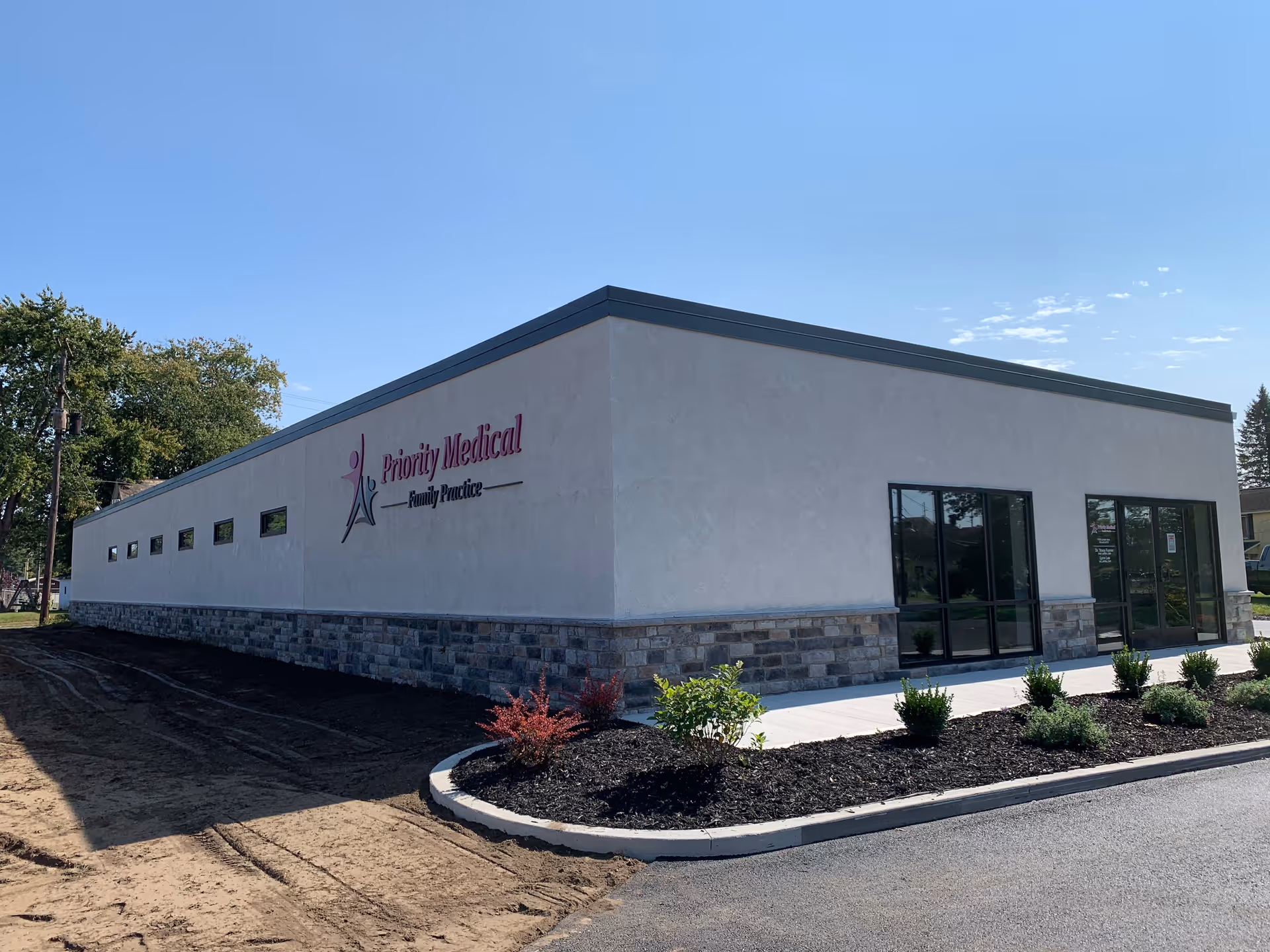 White single-story medical building with glass entrance and landscaped front.