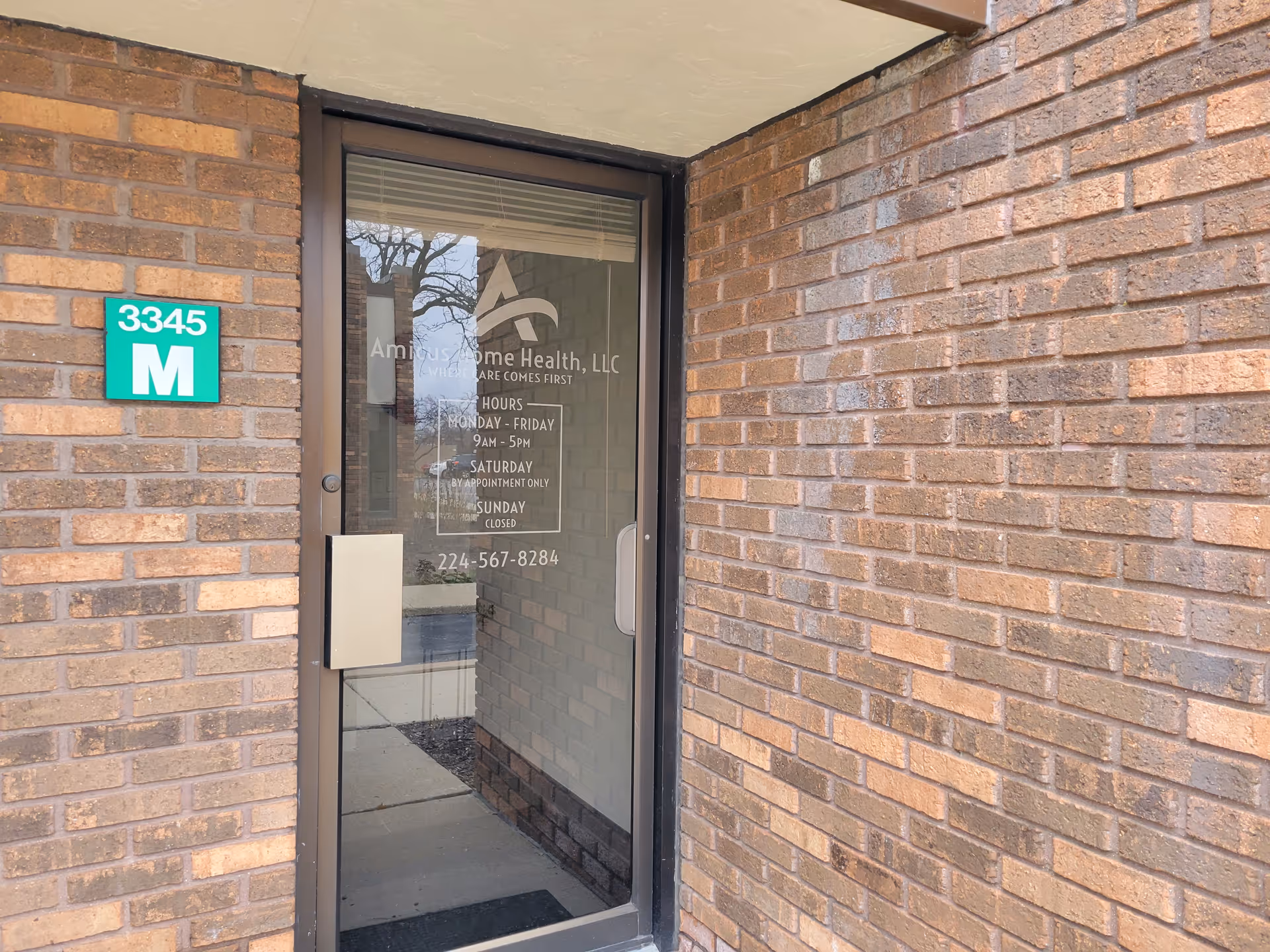 Brick exterior with glass door displaying Amicus Home Health, LLC signage.