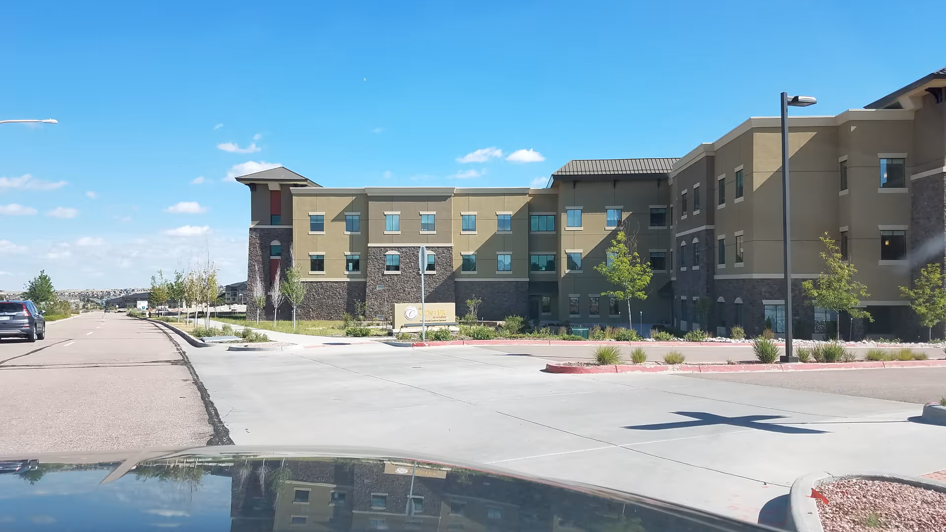 Exterior view of Center at Cordera senior living facility with parking lot and clear blue sky.