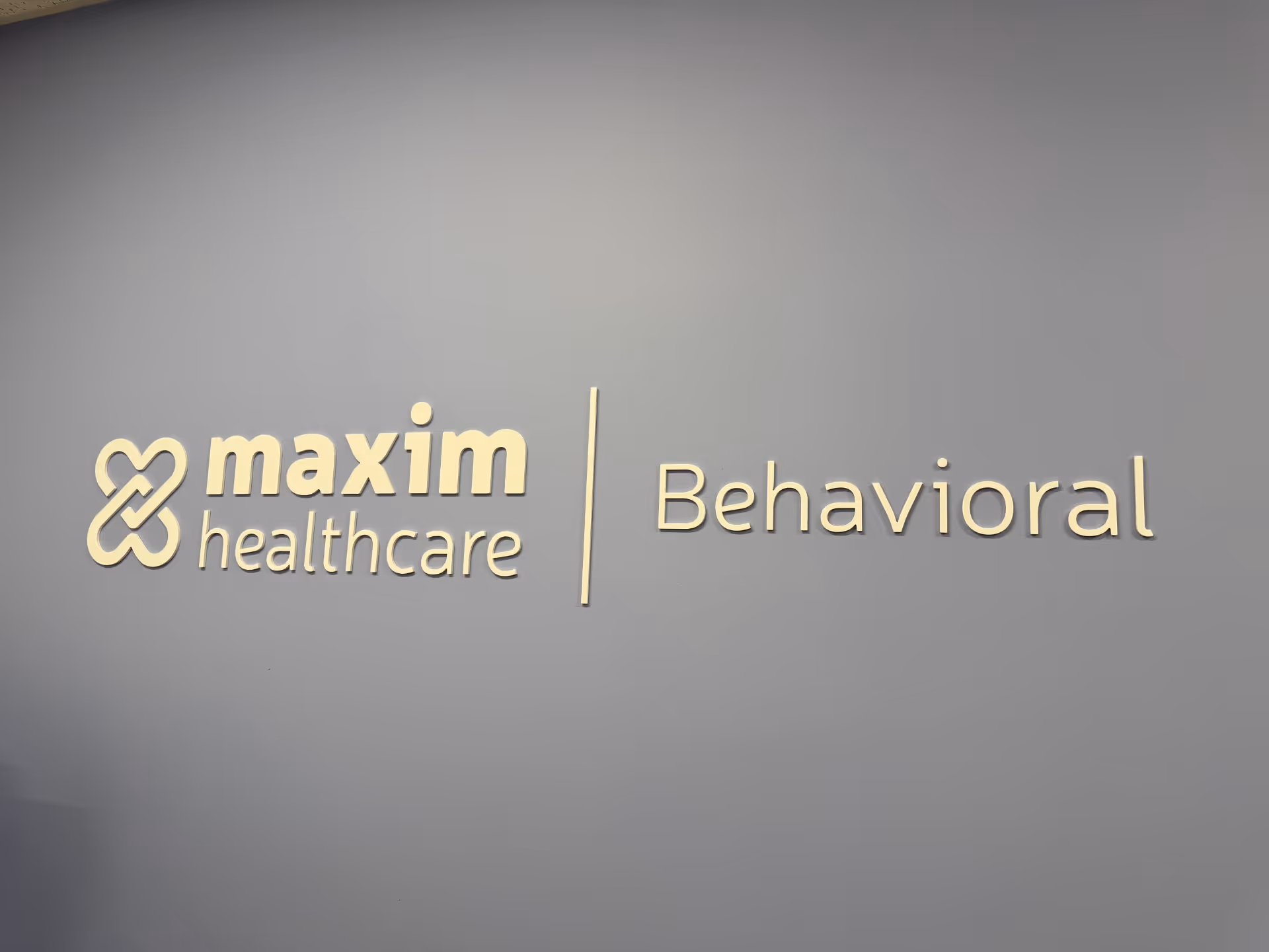 Sign on a blue wall displaying 'Maxim Healthcare | Behavioral'.