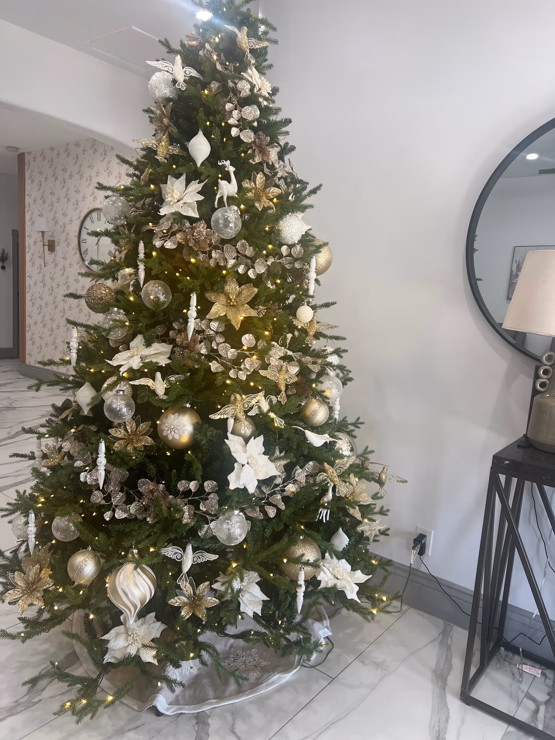 Decorated Christmas tree stands indoors in a facility lobby beside a round mirror.