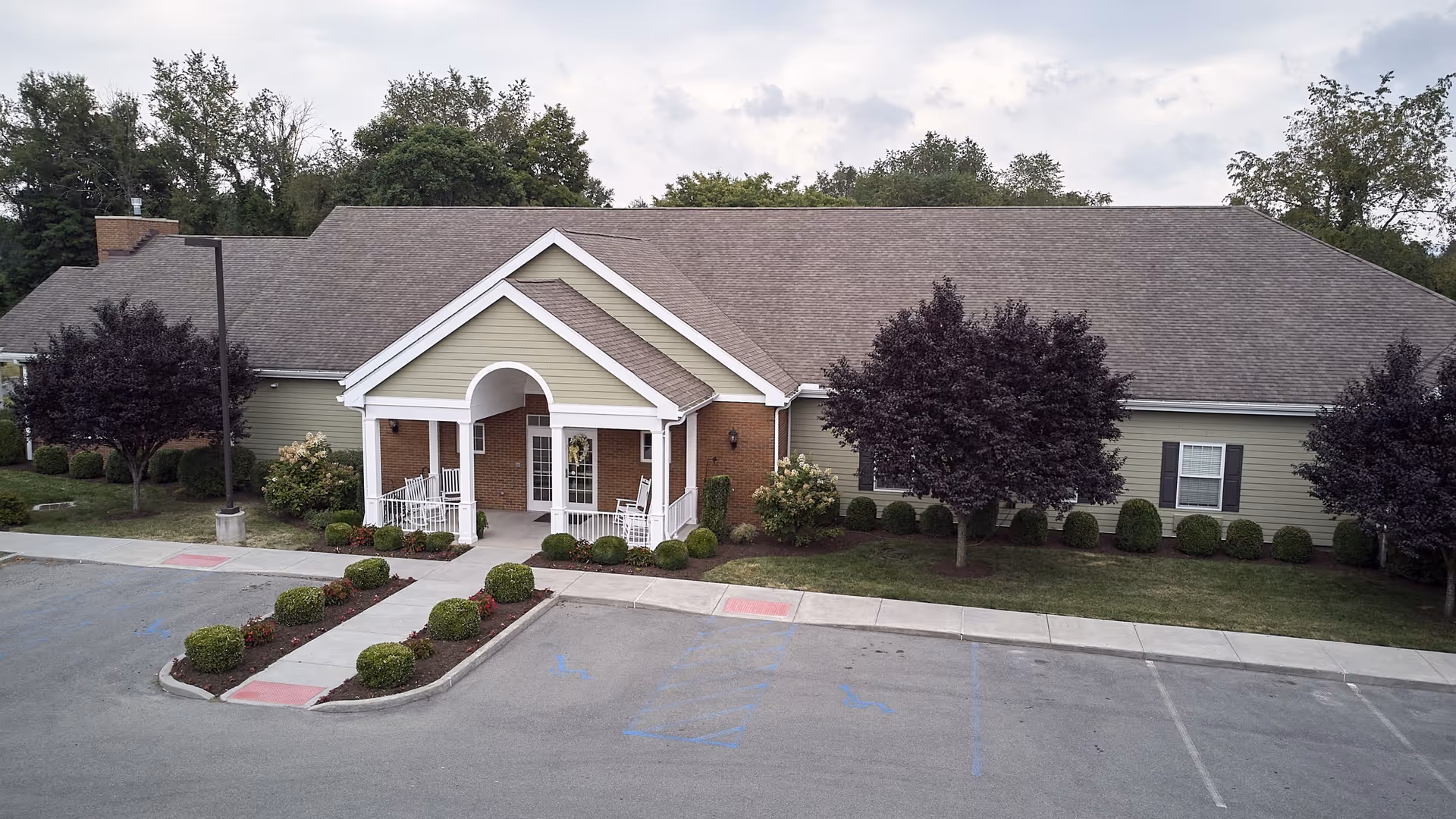 Single-story hospice facility with brick entrance, beige siding, and manicured shrubs along walkway.